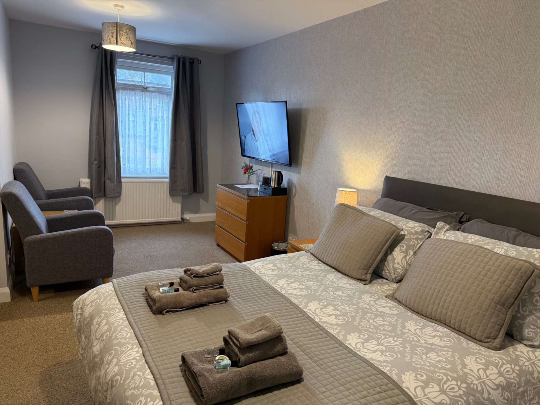 Spacious double room with TV, seating and towels at YO10 Accommodation
